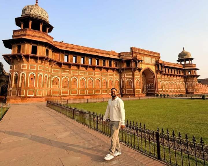 Voyageur sur la pelouse devant le palais de grès rouge Jahangiri Mahal, au fort d'Agra, en Inde