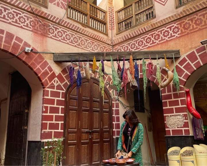 Voyageuse mélangeant des épices dans le patio d'un riad orné de laine teinte à Marrakech