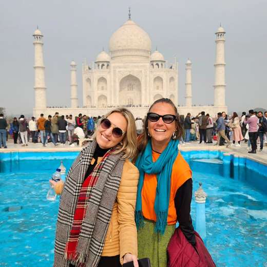 Deux amies en écharpe souriant devant le Taj Mahal, en Inde